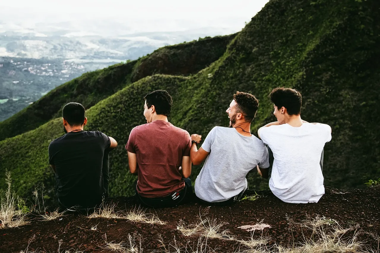 Groupe d'amis assis dans l'herbe face aux collines