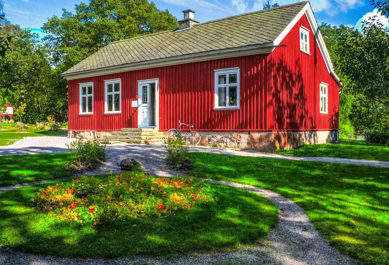 Maison rouge traditionnelle au milieu d'un jardin fleuri, en Suède