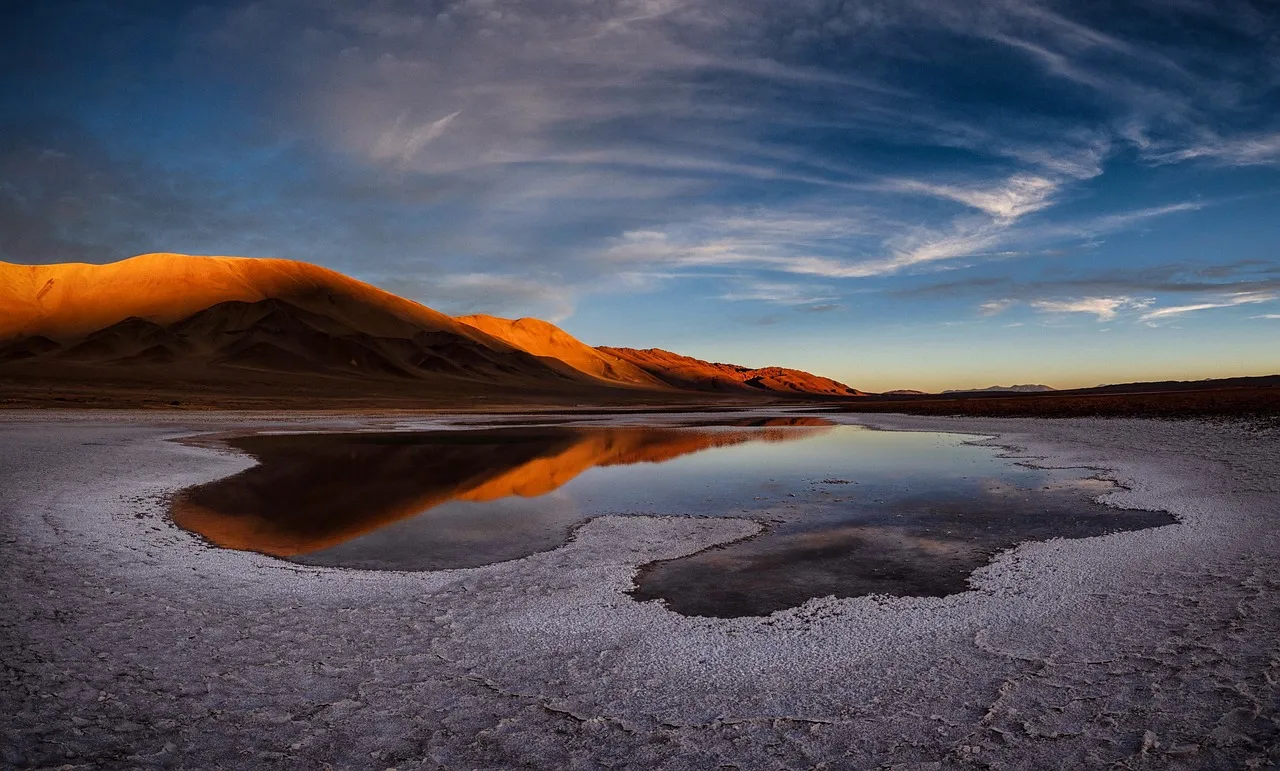 Lagune et dune rougeoyante au coucher du soleil, dans le désert d'Atacama au Chili